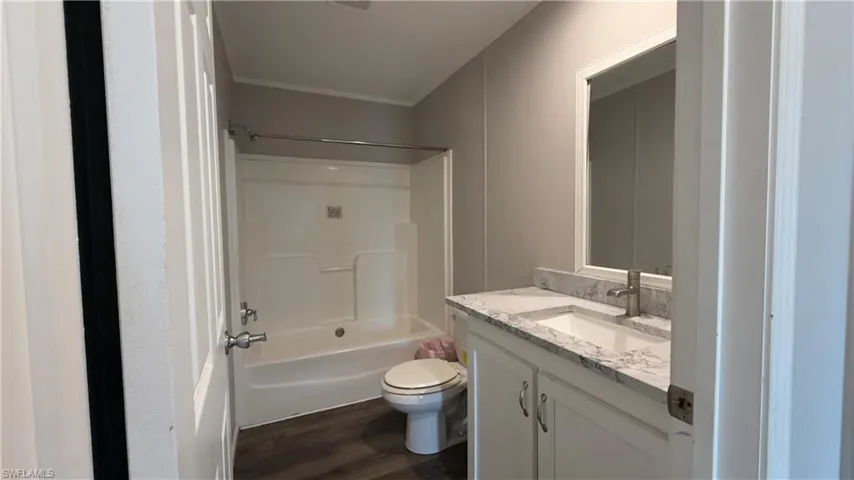 Bathroom with vanity, shower / bath combination, and dark wood-style floors