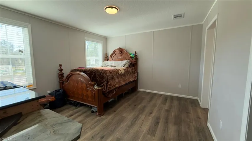 Bedroom featuring a decorative wall, dark wood-style floors, and a textured ceiling