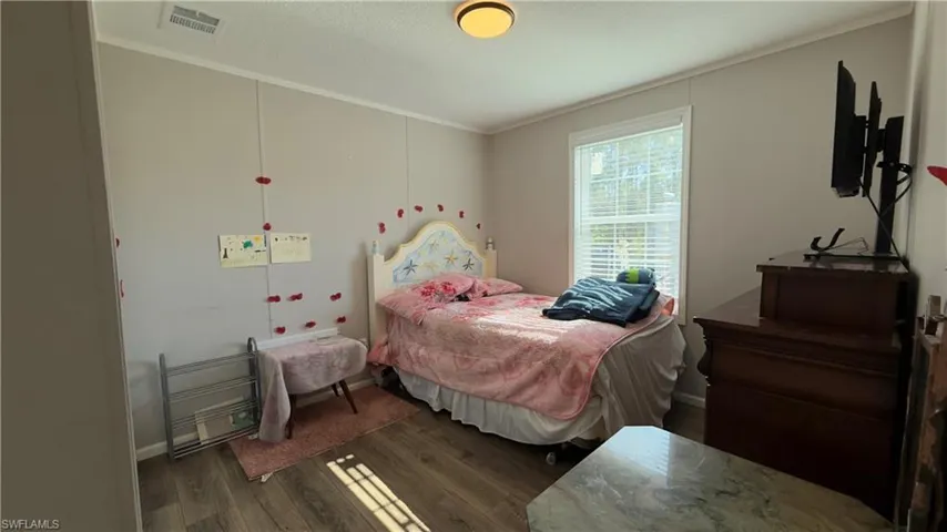 Bedroom featuring dark wood-style floors, ornamental molding, and a textured ceiling