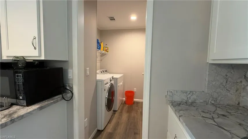 Washroom featuring washer and dryer, dark wood finished floors, and ornamental molding