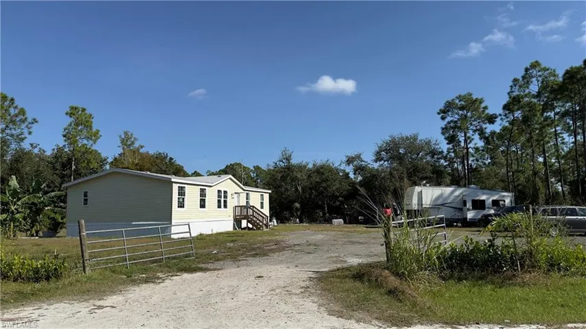 View of dirt / gravel road with a gated entry and view of wooded area