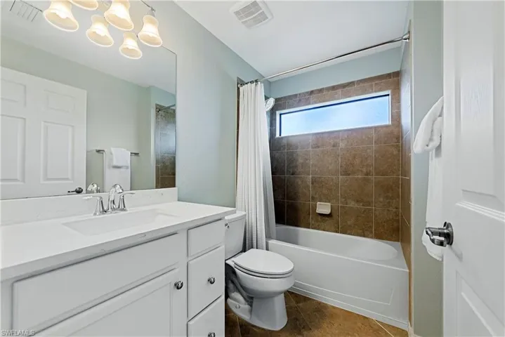Full bathroom with tile patterned flooring, vanity, toilet, and shower / bathtub combination with curtain