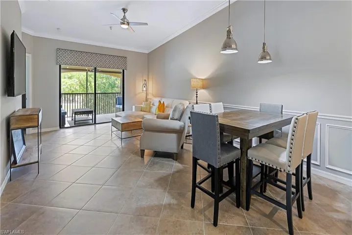 Tiled dining room with ceiling fan and crown molding