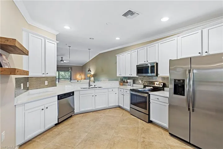 Kitchen featuring appliances with stainless steel finishes, ceiling fan, sink, decorative light fixtures, and white cabinetry