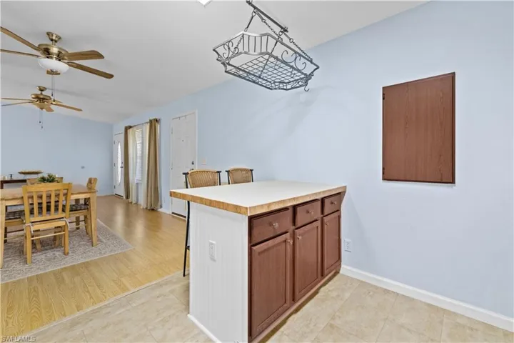 Kitchen with light countertops, a peninsula, ceiling fan, wood finish cabinets, and a breakfast bar area