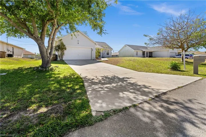 Single story home featuring a garage, a front lawn, driveway, stucco siding, and a residential view