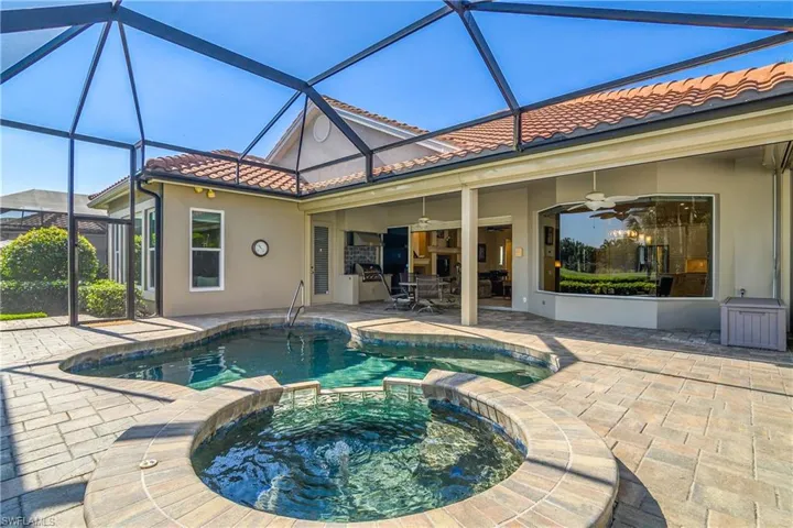 Pool/spa centered on large lanai with gas grill at center left, open great room sliders and kitchen/morning room window at right. Plenty of sun but room to retreat into shade.