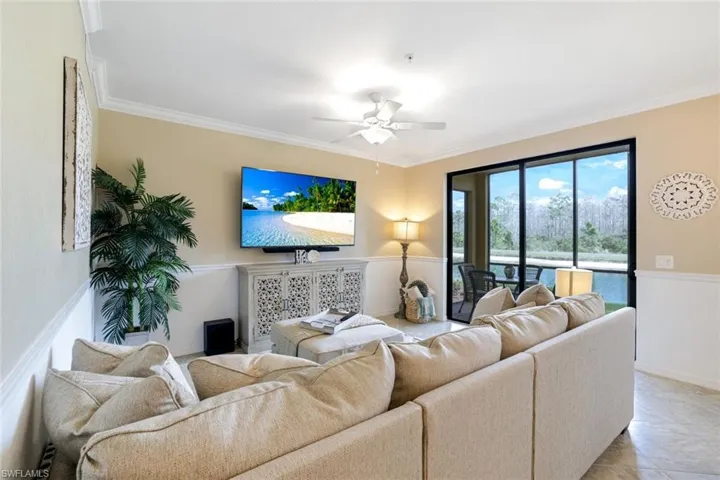Living room featuring ceiling fan, crown molding, chair rail, and tile patterned floors