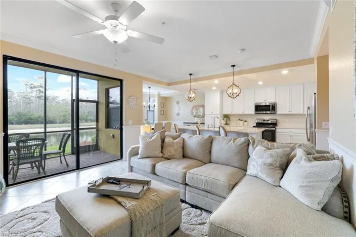 Living room with crown molding, custom lights, ceiling fan, and light tile patterned floors