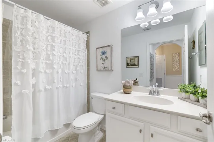 Full bath featuring vanity, shower / bathtub combination with curtain, and light tile patterned floors