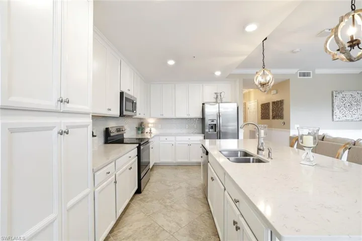 Kitchen with stainless steel appliances, a spacious island, white cabinets, decorative backsplash, and crown molding