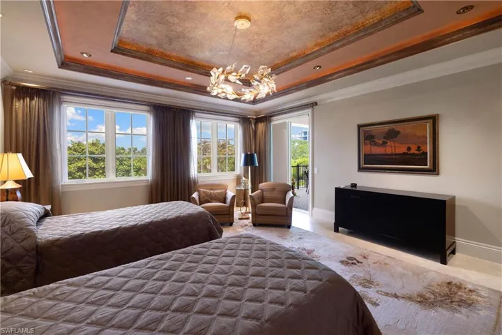 A grand primary bedroom with water views and access to the patio.
