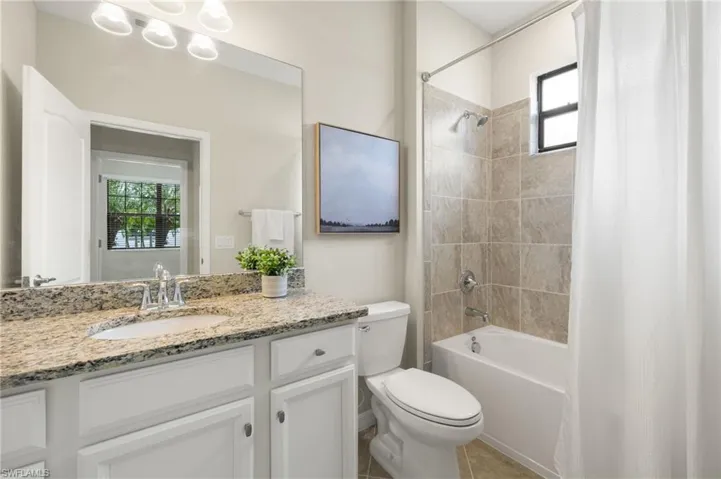 Full bathroom featuring tile floors, shower / tub combo with curtain, toilet, and vanity