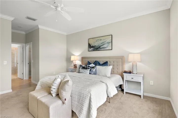 Bedroom with light carpet, ornamental molding, and ceiling fan