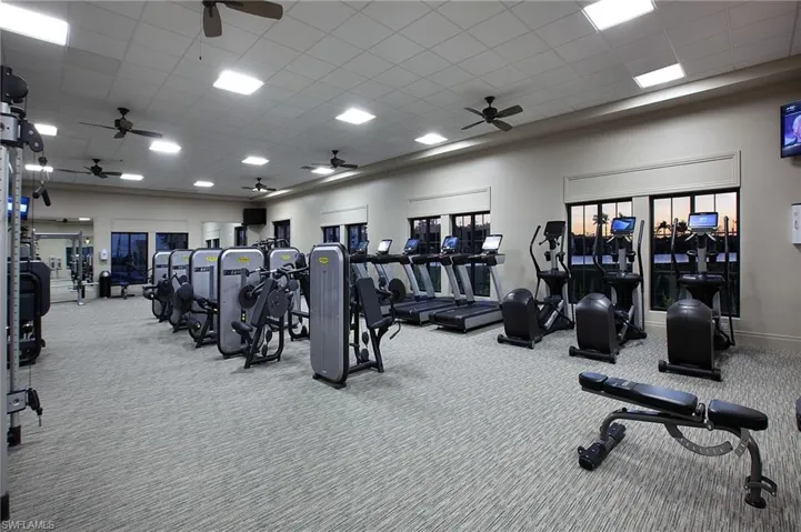 Exercise room with ceiling fan, carpet floors, and a paneled ceiling