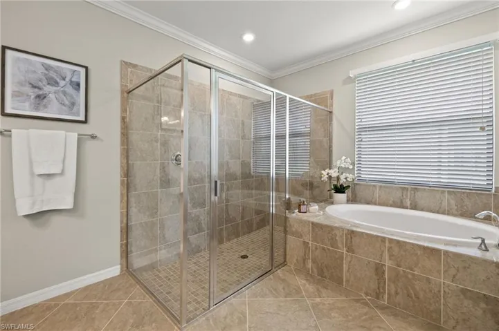 Bathroom featuring tile flooring, ornamental molding, and shower with separate bathtub