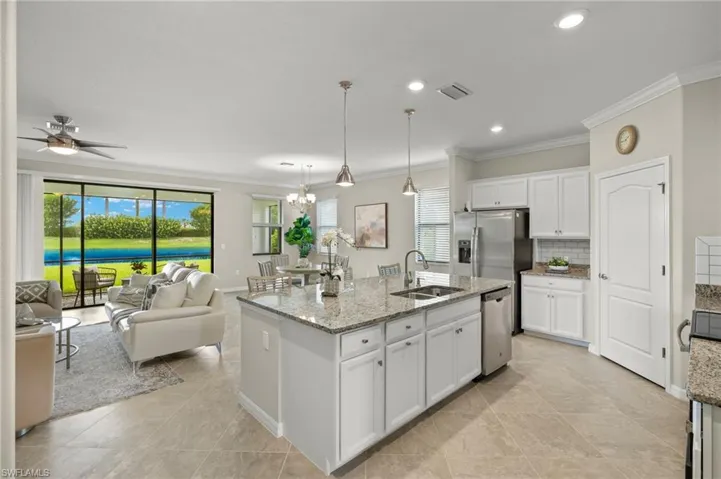 Kitchen featuring white cabinetry, a kitchen island with sink, sink, and pendant lighting