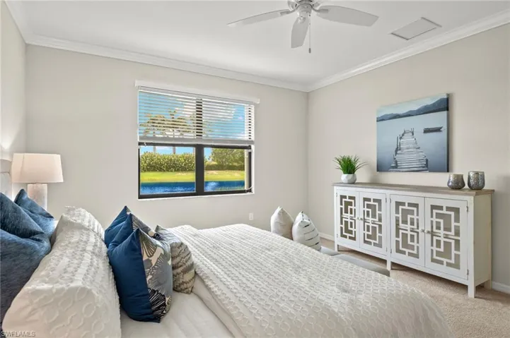 Carpeted bedroom featuring ceiling fan, crown molding, and a water view