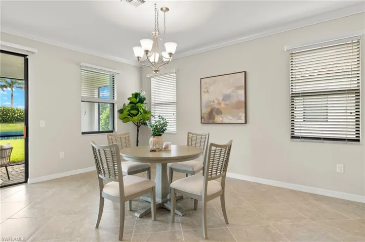 Dining room with a wealth of natural light, an inviting chandelier, light tile flooring, and crown molding