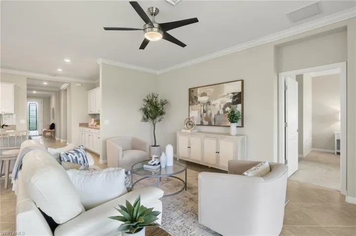 Living room featuring ceiling fan, light tile floors, and crown molding
