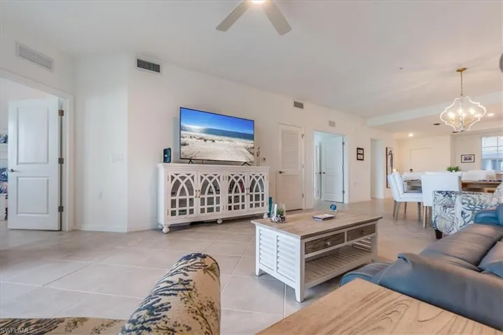 Tiled living room featuring ceiling fan with notable chandelier