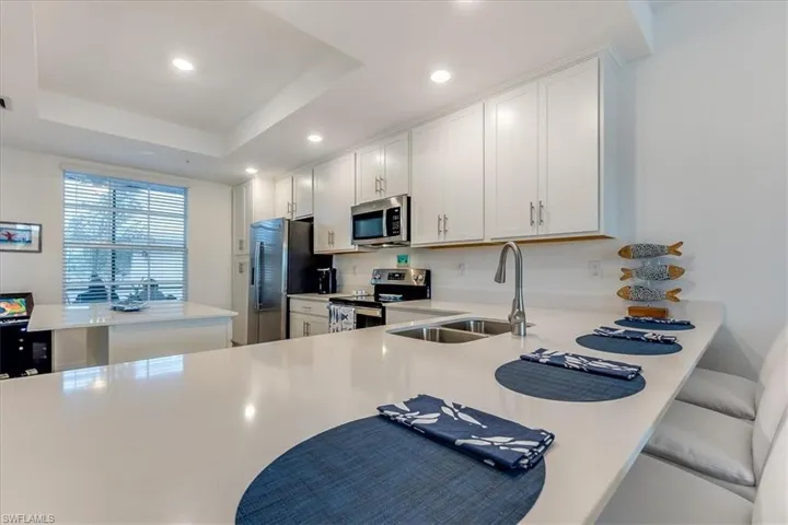 Kitchen featuring a raised ceiling, sink, white cabinets, and appliances with stainless steel finishes