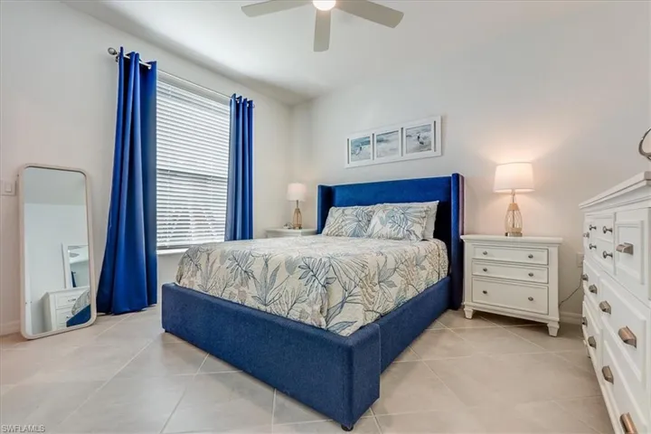 Tiled bedroom with ceiling fan and multiple windows