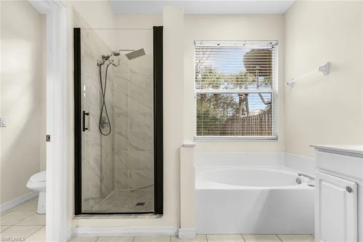 Full bath with vanity, a shower stall, a bath, and light tile patterned floors