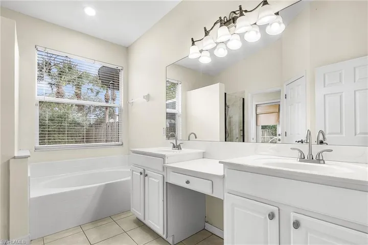 Full bath with double vanity, a bath, light tile patterned floors, and a shower stall
