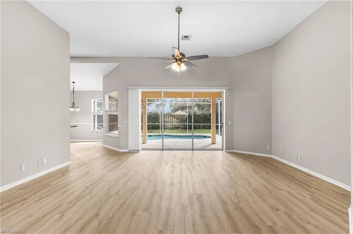 Unfurnished living room with a ceiling fan, light wood-style floors, and a high ceiling
