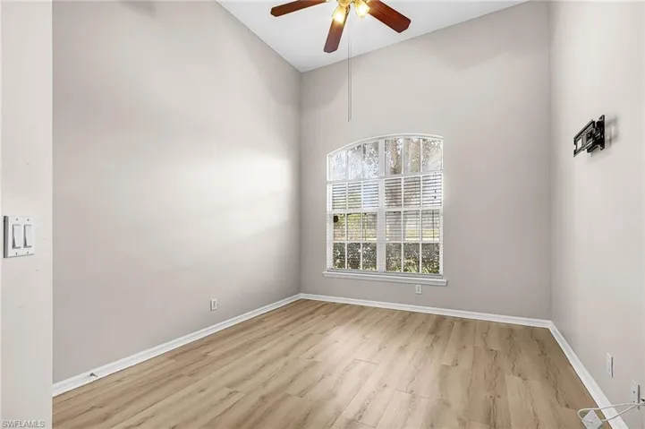 Spare room with a ceiling fan, light wood-type flooring, and lofted ceiling