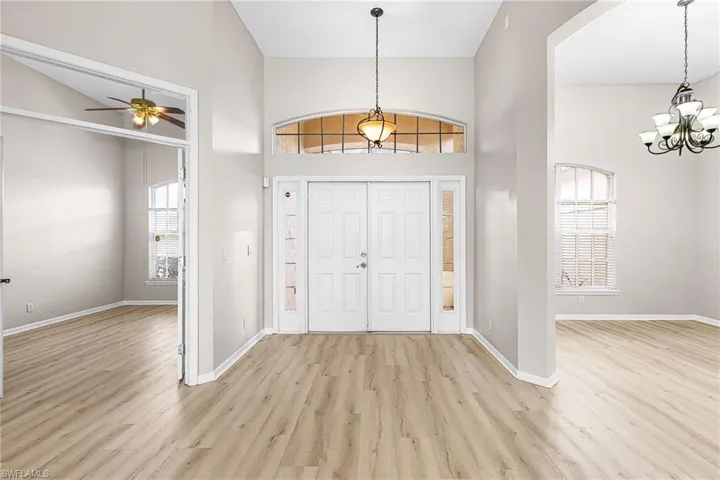 Entryway with ceiling fan, light wood-style floors, a chandelier, and a high ceiling