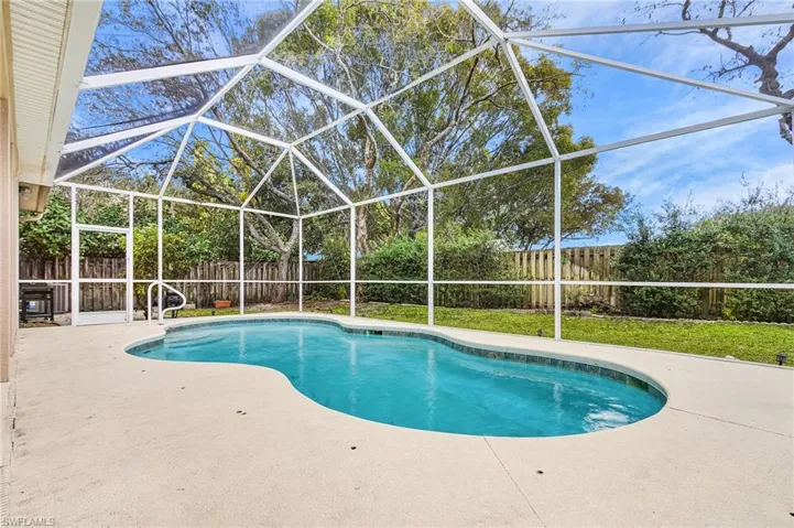 View of swimming pool with a fenced backyard, a sunroom, a lanai, and patio surround
