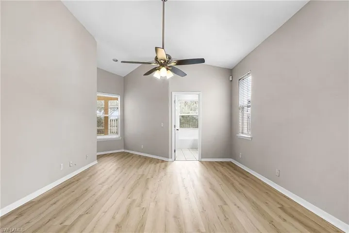 Unfurnished room with light wood-type flooring, lofted ceiling, healthy amount of natural light, and a ceiling fan