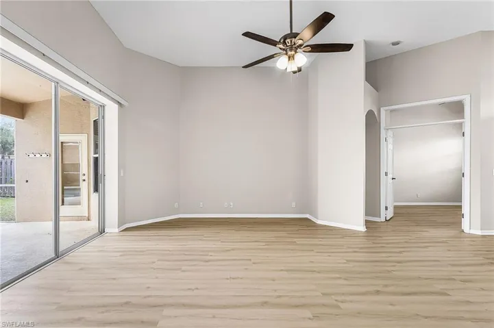 Unfurnished bedroom with light wood-style floors, access to exterior, ceiling fan, and arched walkways