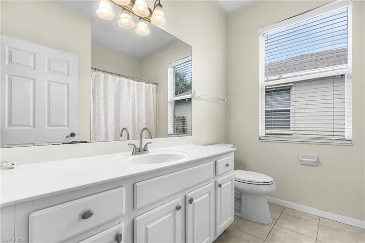 Full bath featuring vanity, a shower with curtain, ornamental molding, and light tile patterned floors