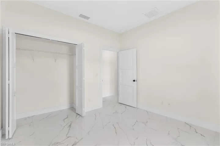 Unfurnished bedroom with light marble finish flooring and a closet