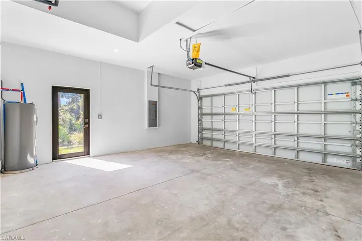 Garage with water heater, electric panel, and a garage door opener