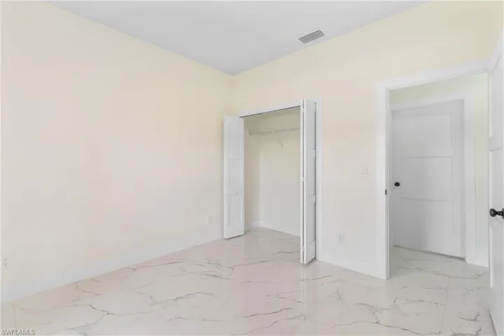 Unfurnished bedroom with light marble finish floors and a closet