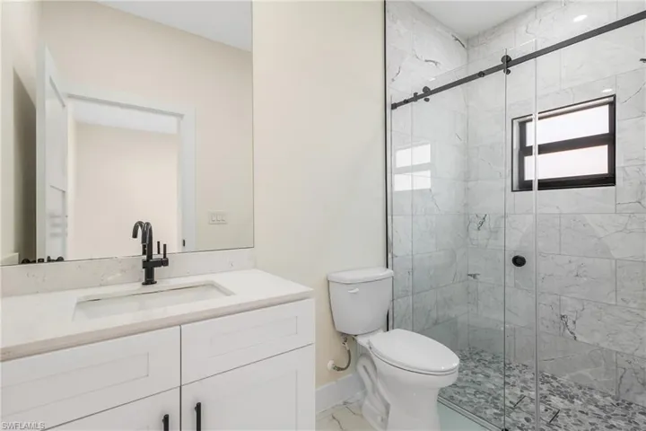Bathroom with a marble finish shower and vanity