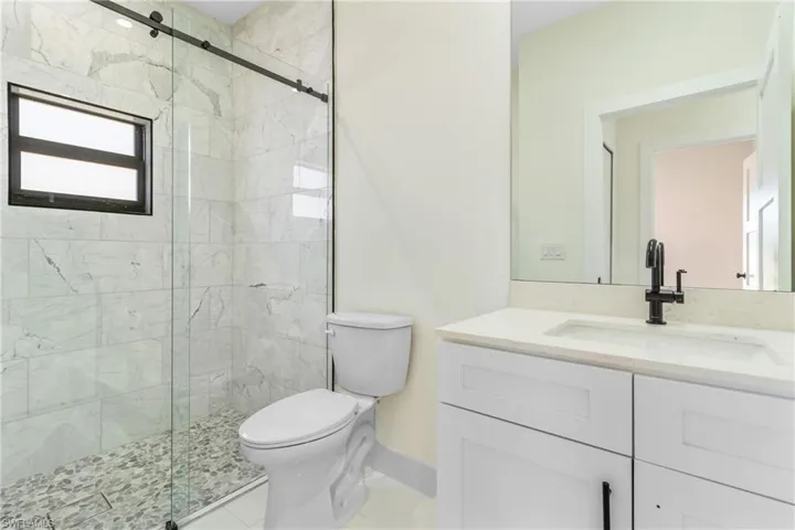 Bathroom with vanity, a marble finish shower, and light tile patterned flooring