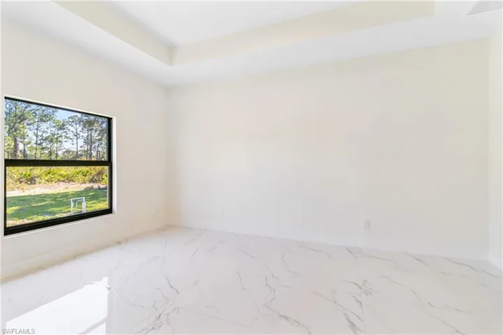 Unfurnished room featuring marble look tiles and a raised ceiling