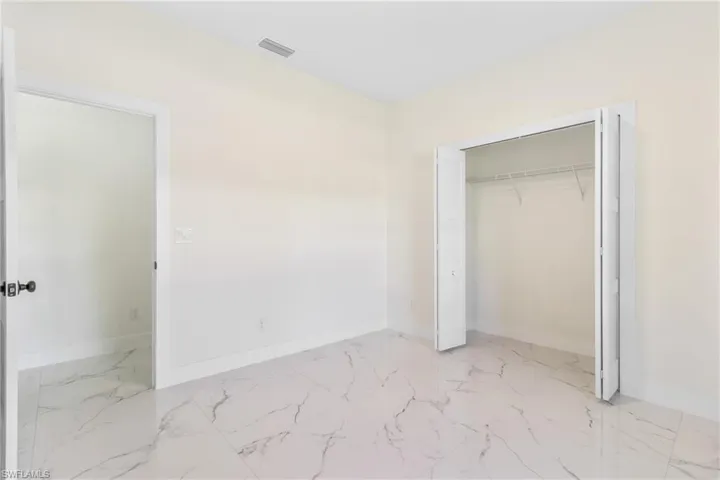 Unfurnished bedroom featuring light marble finish flooring and a closet