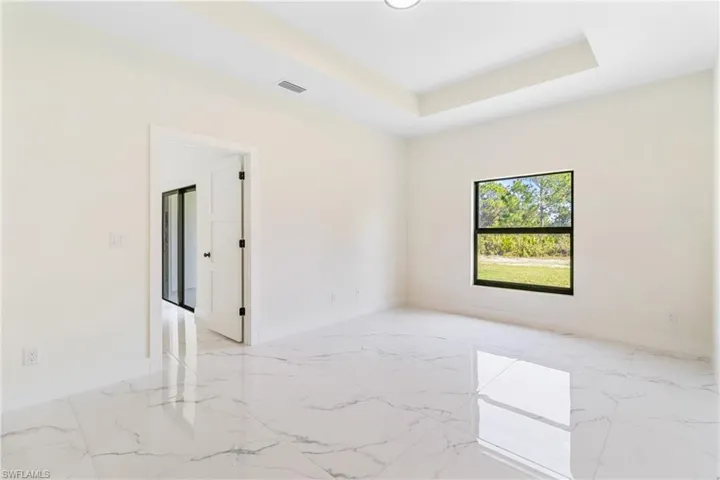 Empty room with light marble finish floors and a tray ceiling