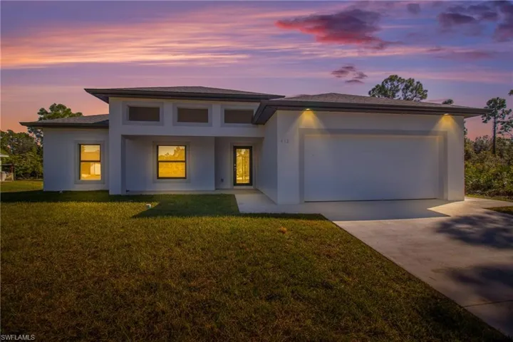 Prairie-style home featuring concrete driveway, a yard, stucco siding, and a garage