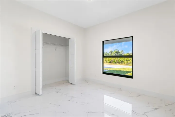 Unfurnished bedroom with light marble finish floors and a closet