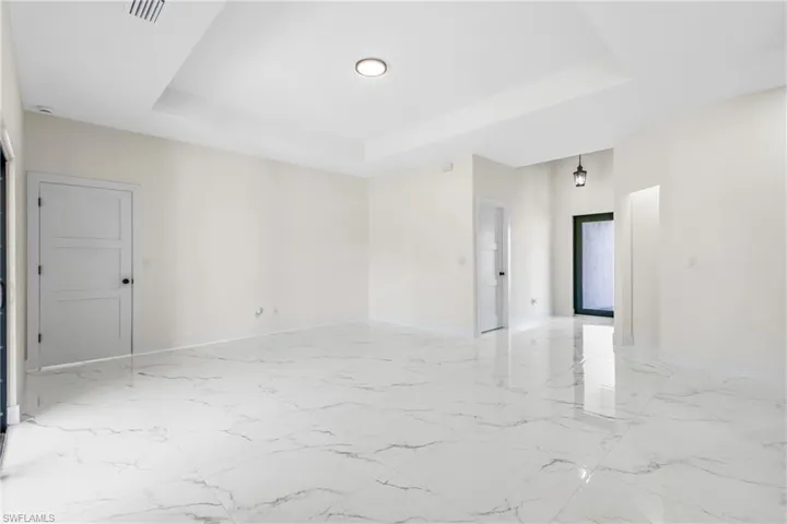 Unfurnished room with a raised ceiling and light marble finish floors