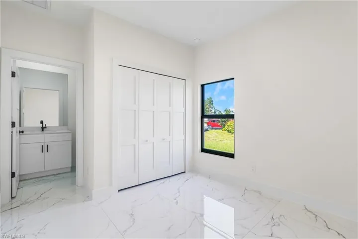 Unfurnished bedroom with light marble finish floors, ensuite bathroom, and a closet