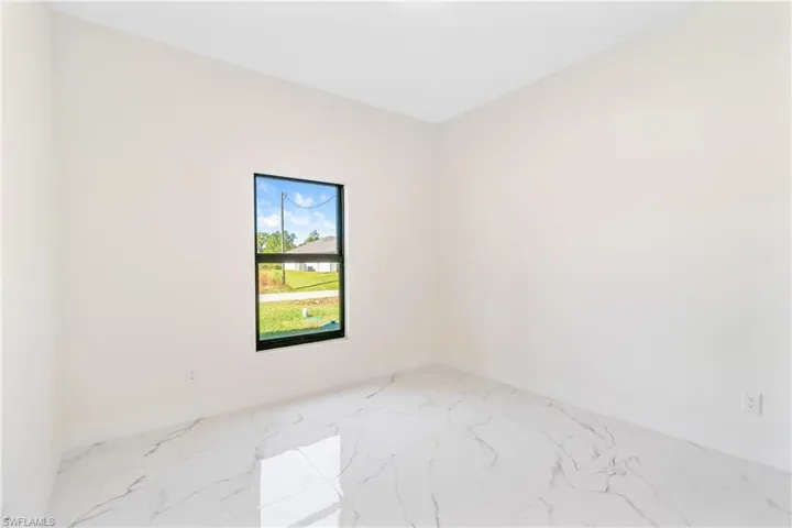 Unfurnished room featuring light marble finish flooring and baseboards
