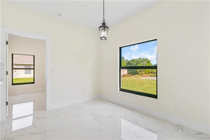 Spare room featuring light marble finish floors and baseboards